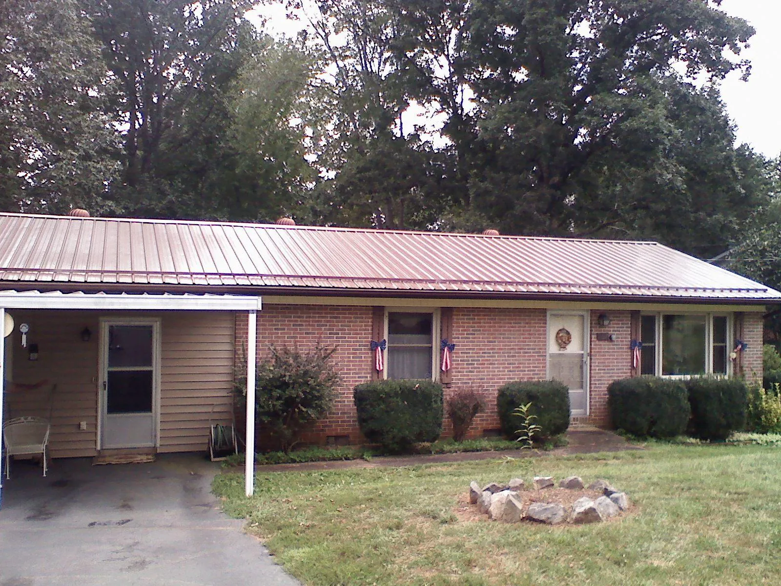 Bronze metal roof and carport on a brick ranch home — Roof Repair work by our crew in Freeman